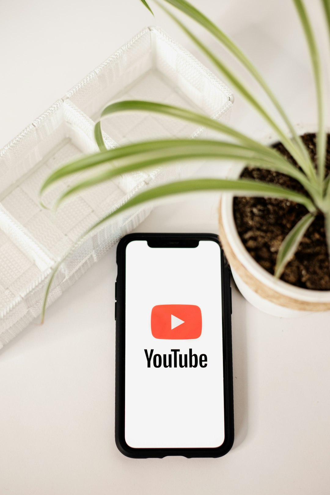 a-phone-with-a-youtube-logo-on-it-next-to-a-potted-plant-a2h11ygtru